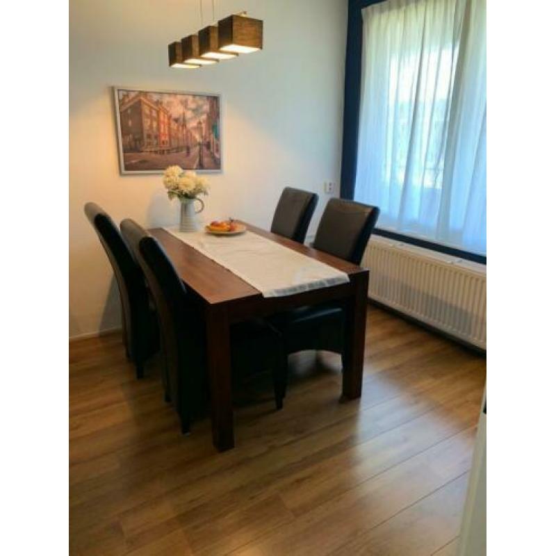 Mooie teak houten eettafel met vier zwart lederen stoelen